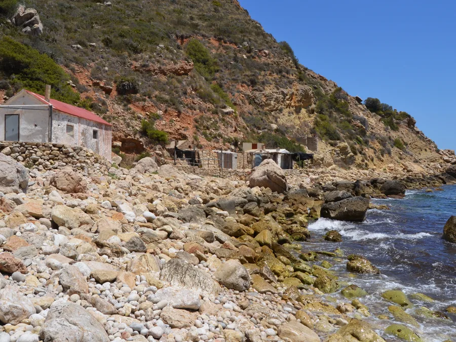 La cala del Llebeig, con las casetas de pescadores junto a los cantos rodados