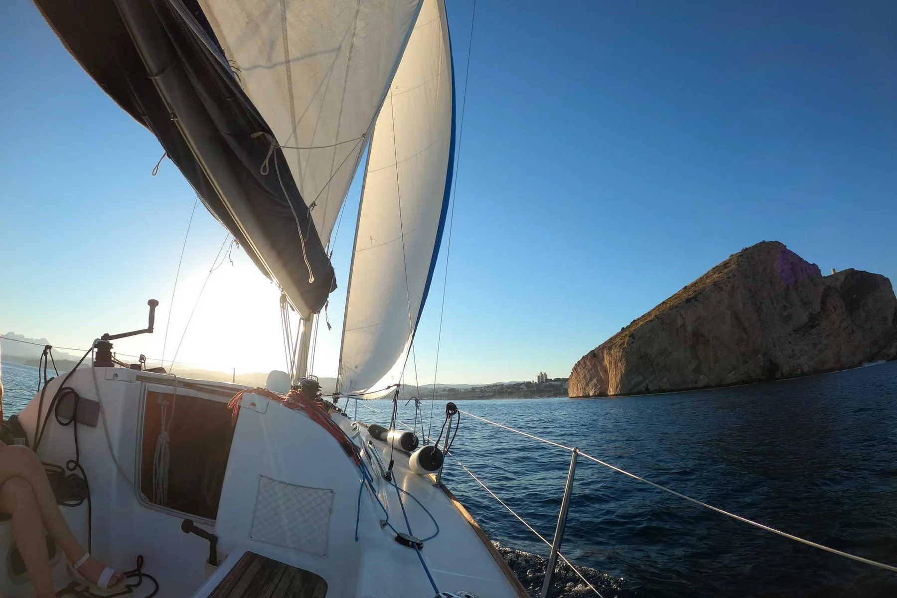 A sailing boat leaving Moraira with Cap d'Or in view